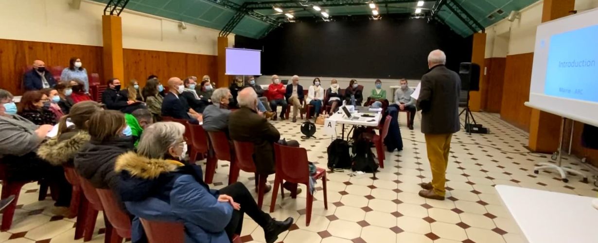 photo représentant des gens assis en arc de cercle dans une salle écoutant un intervenant