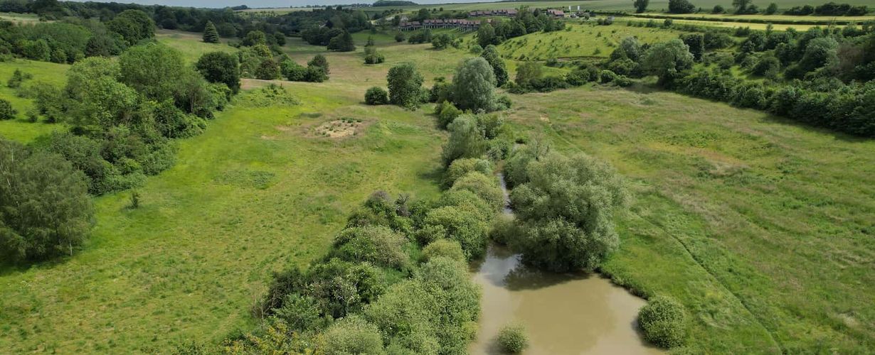 vue aérienne du Domaine du val, plan d'eau et grandes études d'herbes, arbres et au loin les maisons sur pilotis